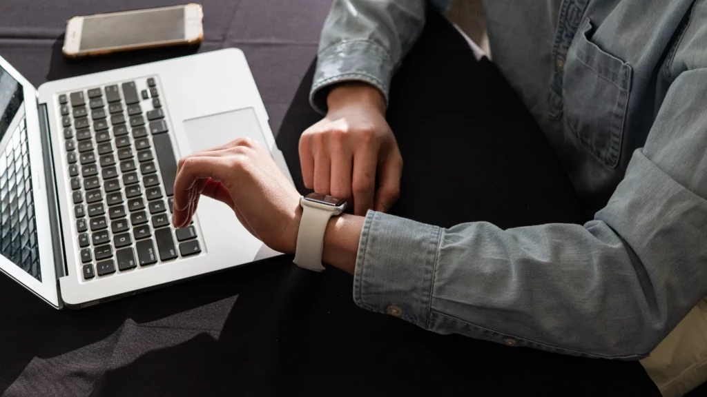 Lehrer sitzt vor einem Laptop und schaut auf die Uhr